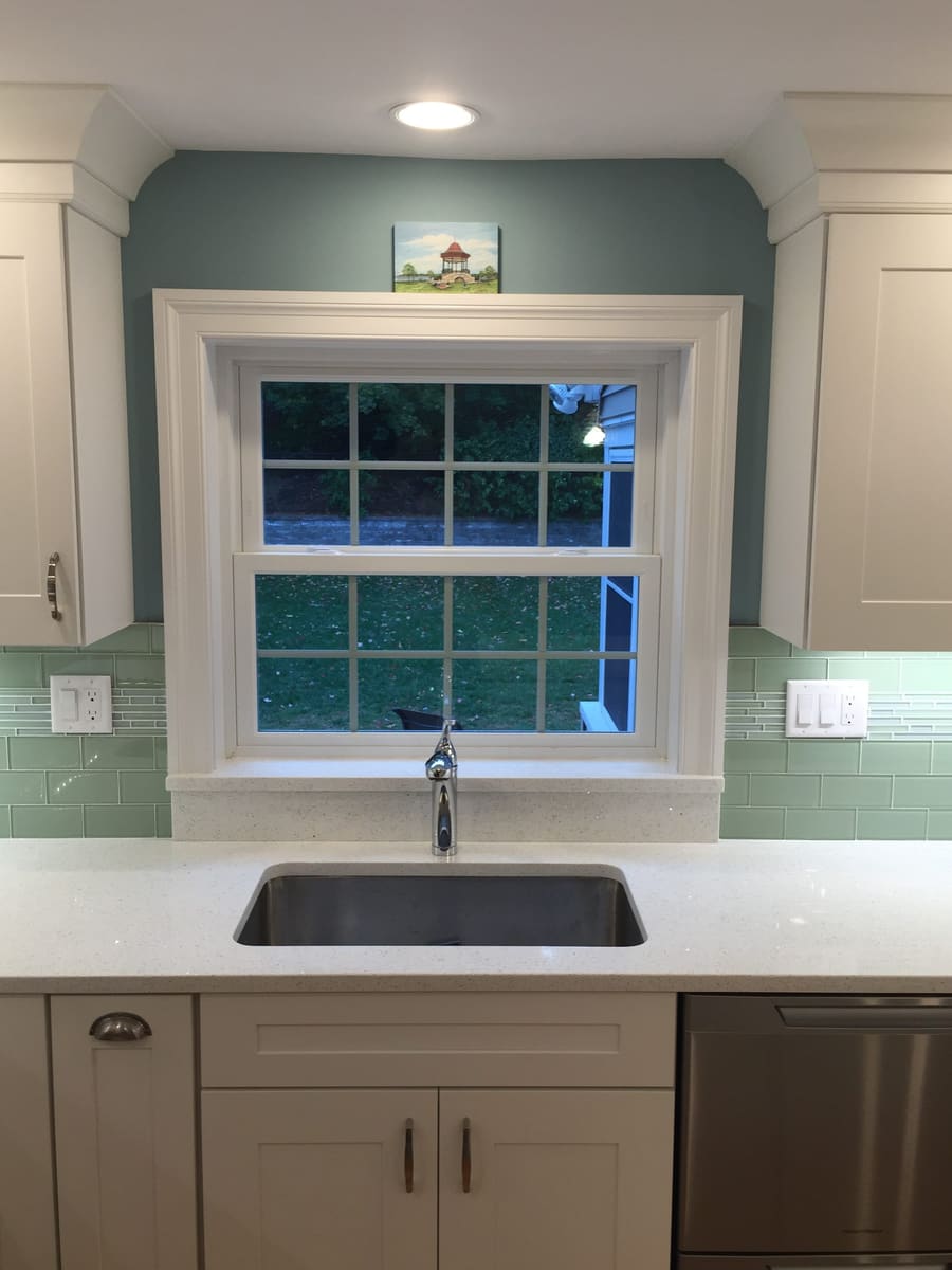 Sink under the window, with a green subway-tile backsplash